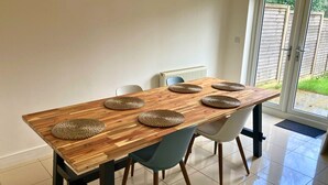 Ein Esstisch mit sechs gewebten Platzsets, zwei blauen Stühlen und einem Heizkörper im Hintergrund.