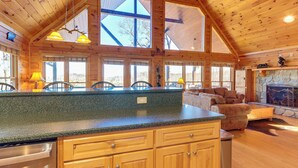 A spacious kitchen with a large island, wooden cabinets, and a stone fireplace. - Gorgeous Blue Ridge Mountain Retreat: Deck + View! (Blue Ridge)