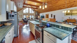 A spacious kitchen with wooden beams, a large island, and a dining area with a view. - Cabin w/ Hot Tub and Wifi: 4 Mi to Snowshoe Resort (Cass)