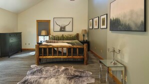 A bedroom with a wooden bed, a large painting, a candelabra, and a dresser.