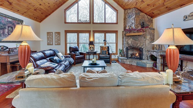 A spacious living room with a high ceiling, a stone fireplace, leather sofas, and large windows. - Cabin w/ Hot Tub and Wifi: 4 Mi to Snowshoe Resort (Cass)