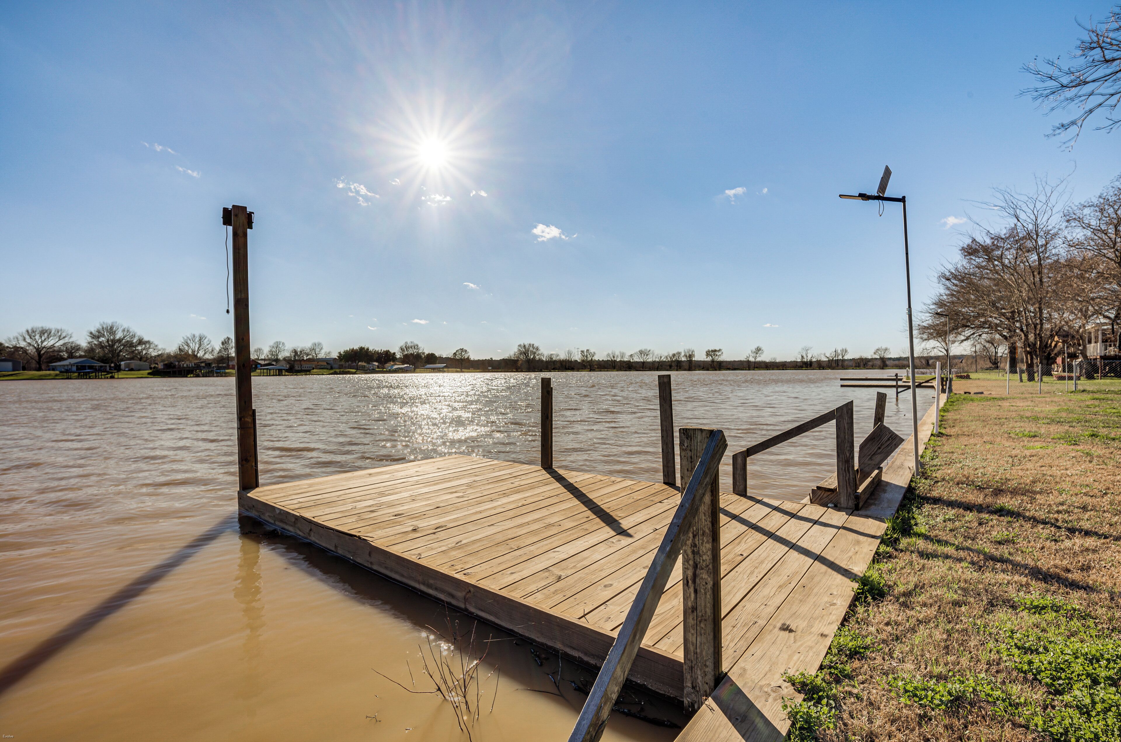 A wooden dock extending into a body of water with a clear sky above.