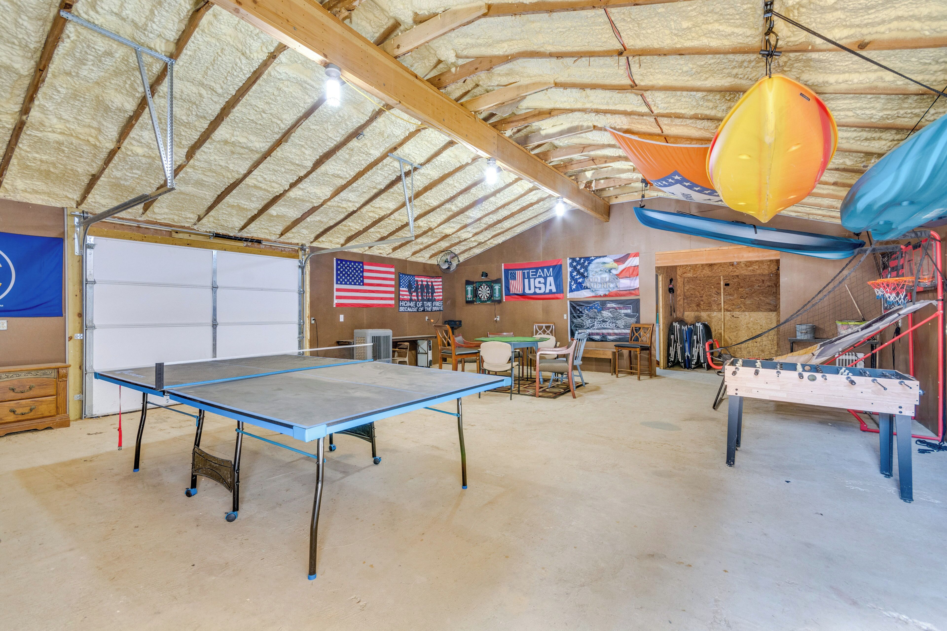 A spacious indoor area with a ping pong table, a foosball table, and various flags including the USA flag.