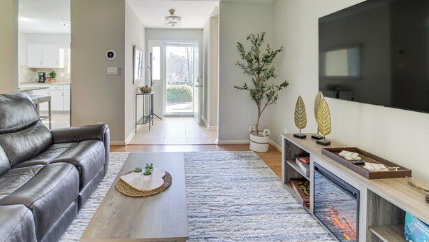 A modern living room with a leather sofa, a coffee table with a plant, a flat-screen TV, and a fireplace. - Lovely Charlotte Home w/ Yard: 9 Mi to Uptown! (Charlotte)