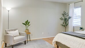 A bedroom with a bed, a chair, a floor lamp, and two potted plants. - Lovely Charlotte Home w/ Yard: 9 Mi to Uptown! (Charlotte)