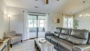 A living room with a sofa, a coffee table, a lamp, and a sliding glass door leading to a balcony. - Lovely Charlotte Home w/ Yard: 9 Mi to Uptown! (Charlotte)