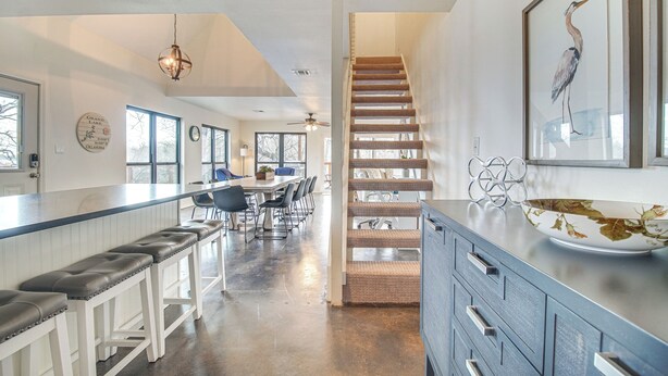 A spacious kitchen with a long counter, bar stools, and a staircase leading to another level. - Deck + Kayaks: Grand Lake of the Cherokees Home (Afton)