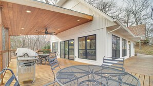 A covered outdoor deck with a metal table and chairs, a grill, and a ceiling fan. - Deck + Kayaks: Grand Lake of the Cherokees Home (Afton)