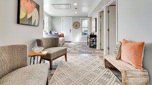 A modern living room with a sofa, armchair, and a coffee table. There is a patterned rug on the floor and a painting on the wall. - Waterfront Buckeye Lake Home w/ Deck & Dock! (Buckeye Lake)