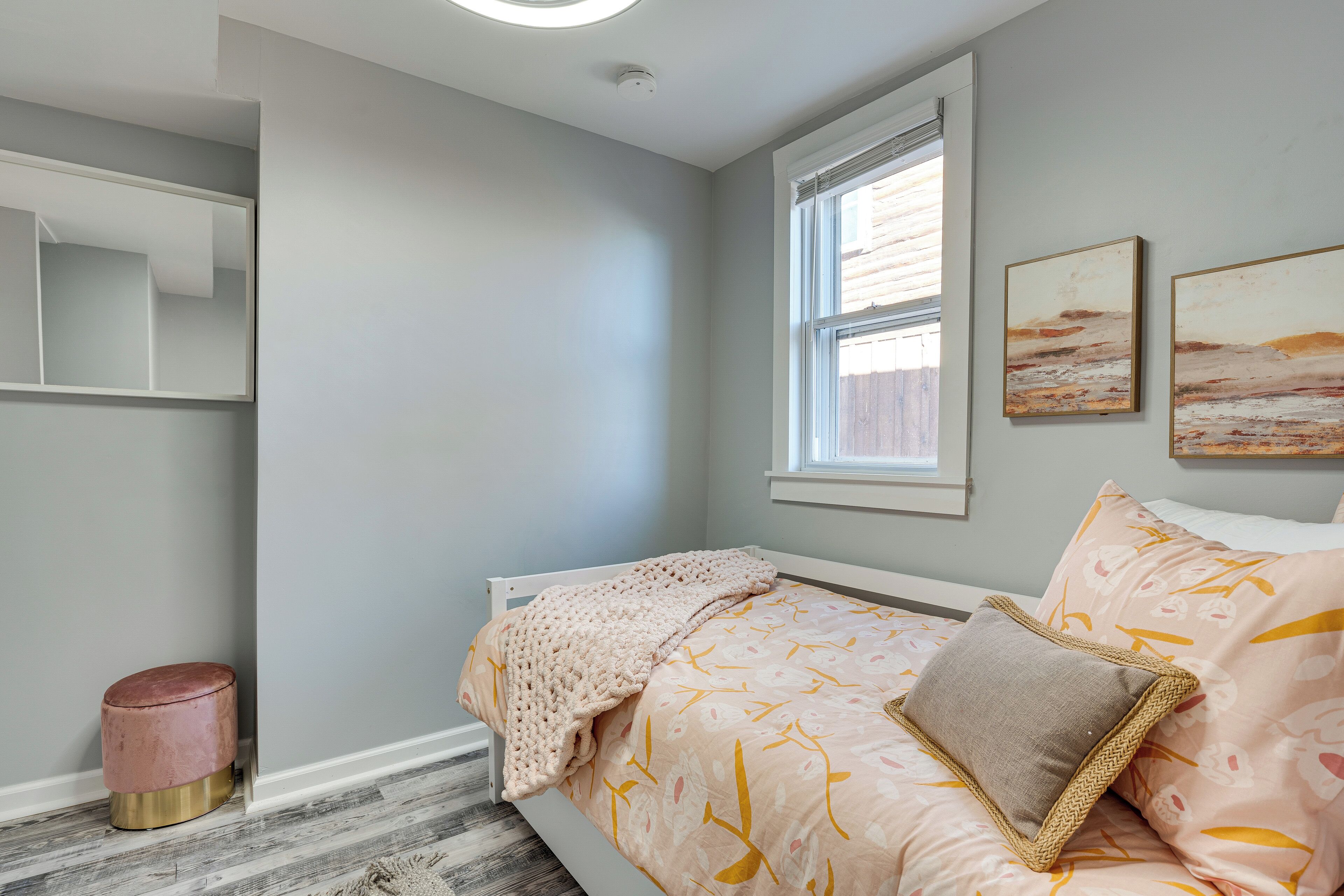 Een slaapkamer met een bed, een raam en een spiegel aan de muur.