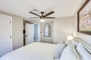 A hotel room with a bed, a ceiling fan, a mirror, and a framed picture on the wall.