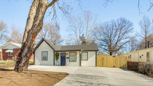 Une maison de plain-pied avec un jardin devant, une clôture en bois et un arbre.