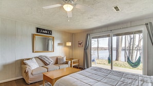 A bedroom with a bed, a sofa, a table, a window with a view of trees and a hammock outside. - Lakefront Moneta Home w/ Community Dock! (Moneta)