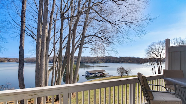 A deck with a view of a lake, trees, and a dock with a boat. - Lakefront Moneta Home w/ Community Dock! (Moneta)