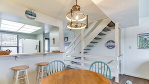 A dining area with a wooden table and chairs, a hanging light fixture, a staircase, and a wall-mounted clock. - Lakefront Moneta Home w/ Community Dock! (Moneta)