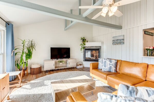 A modern living room with a fireplace, a television, and a sofa. - Beautiful Wells Cottage: Steps to Moody Beach! (Wells)