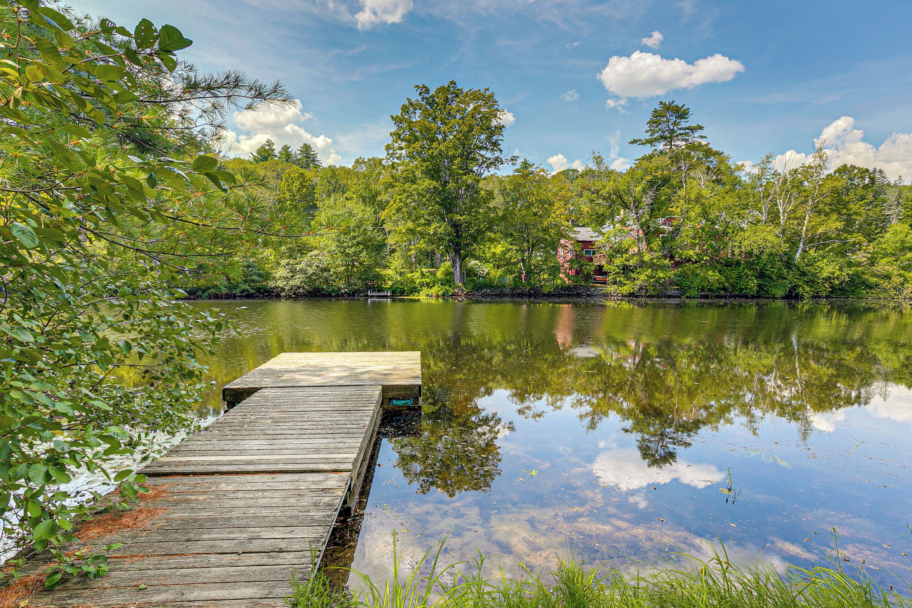 A wooden dock extending into a calm lake surrounded by dense trees.