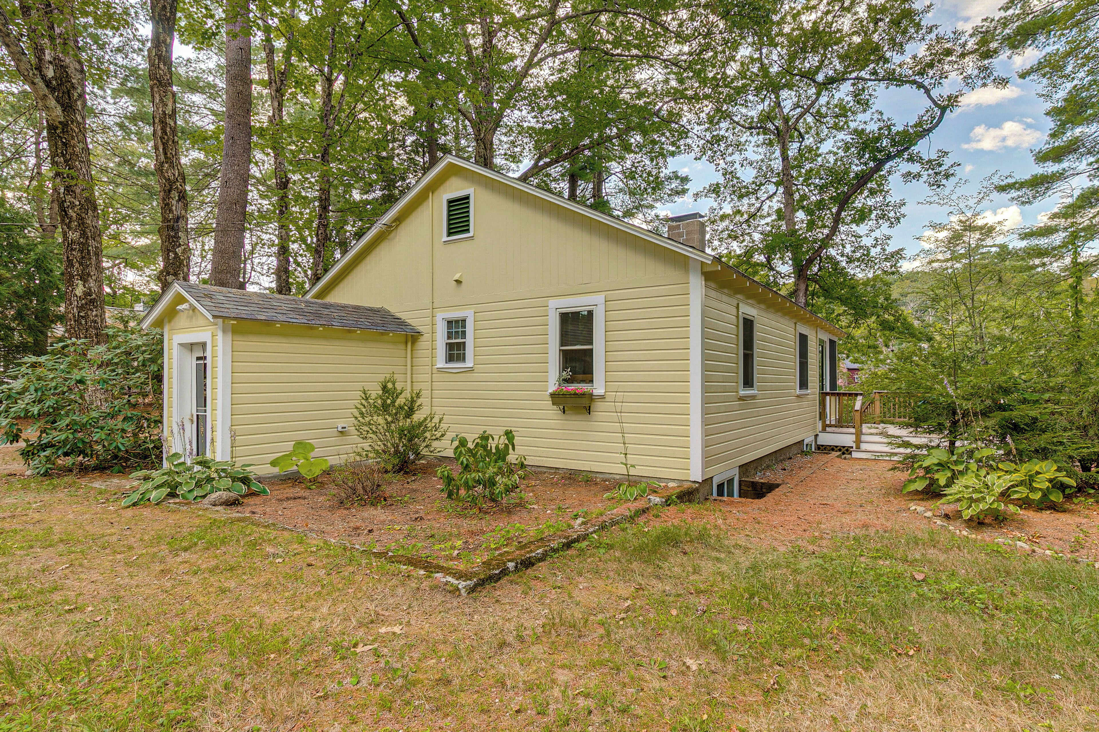 A two-story house with a front porch, surrounded by trees and a grassy yard.