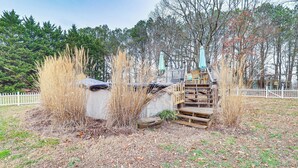 A rustic cabin with a wooden staircase leading to a loft area, surrounded by tall grasses and trees. - Spacious Trappe Getaway w/ Outdoor Pool & Gazebo! (Trappe)