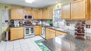 A kitchen with wooden cabinets, stainless steel appliances, a granite countertop, and a backsplash with a fish design. - Spacious Trappe Getaway w/ Outdoor Pool & Gazebo! (Trappe)