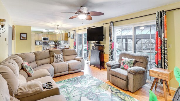 A spacious living room with a sectional sofa, a single armchair, and a coffee table. A ceiling fan and a flat-screen TV are mounted on the wall. - Spacious Trappe Getaway w/ Outdoor Pool & Gazebo! (Trappe)