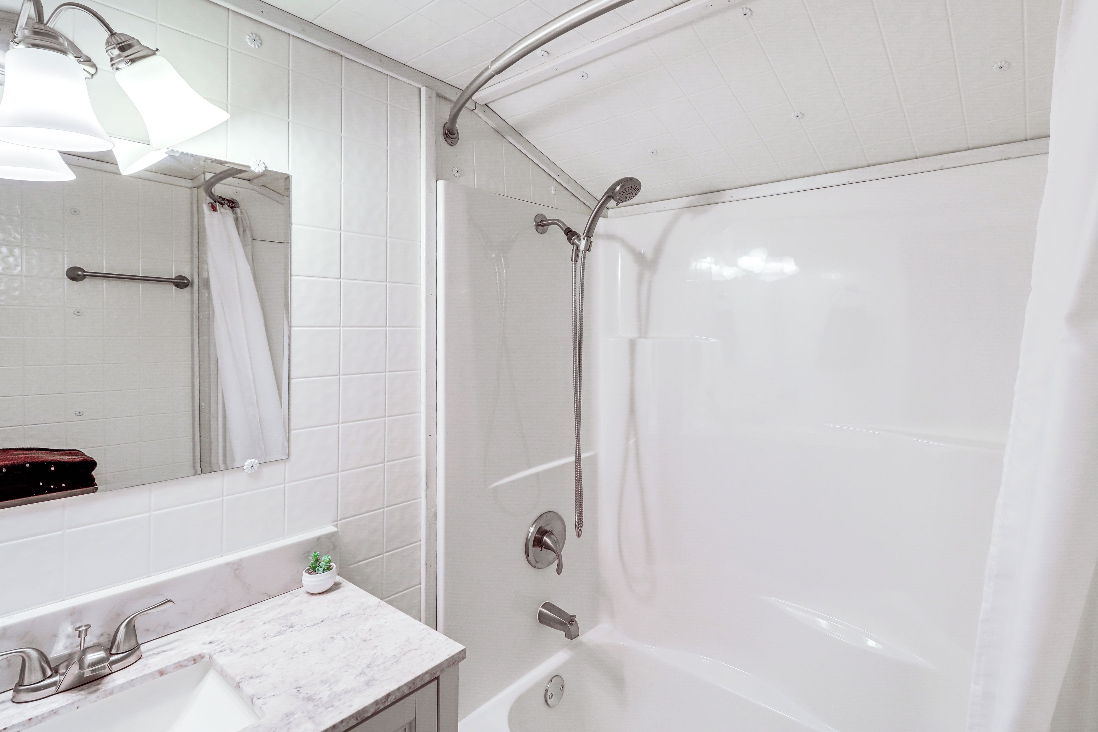 Un baño con bañera, ducha, lavabo con espejo y perchero para toallas.