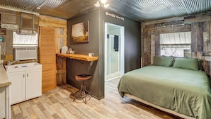 Een rustieke kamer met een bed, een kitchenette en een badkamer.