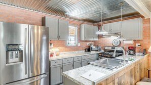 Een moderne keuken met roestvrijstalen apparatuur, een granieten aanrechtblad en een bakstenen muur.
