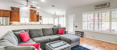 A spacious living area with a sectional sofa, ottoman, and a ceiling fan.