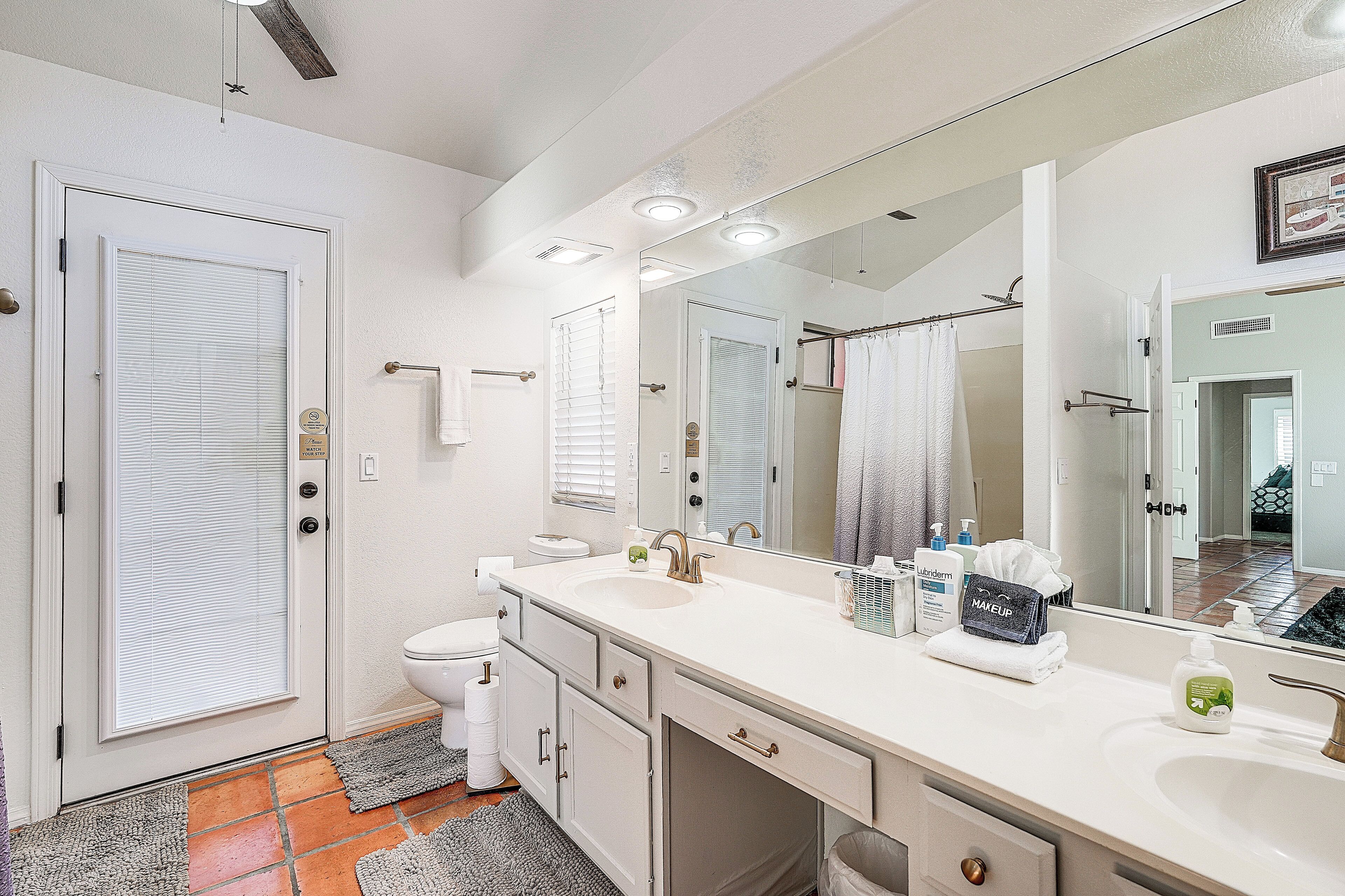 Une salle de bain moderne avec un grand miroir, un lavabo blanc et des toilettes.