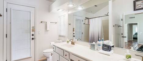 Une salle de bain moderne avec un grand miroir, un lavabo blanc et des toilettes.