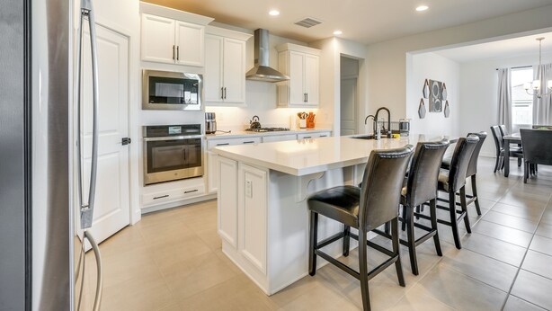A modern kitchen with white cabinetry, stainless steel appliances, and a central island with bar stools. - 5 Mi to Westgate! Newly Built Family Retreat (Glendale)