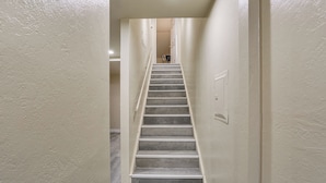 A narrow, well-lit stairway with a handrail, leading to a landing with a door at the top. - Charming Lakehead Cabin: Walk to Shasta Lake! (Lakehead)