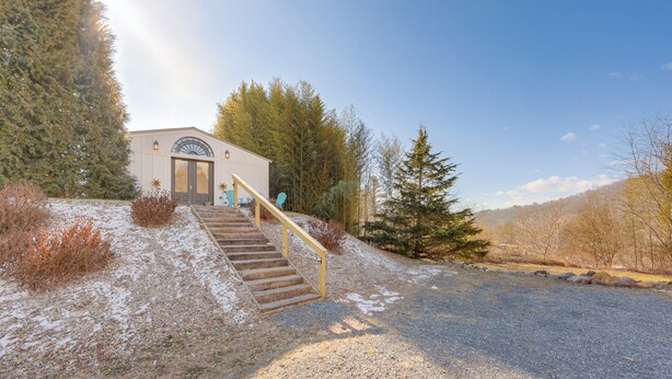 A building with a staircase leading to a door, surrounded by trees and a gravel driveway. - Waynesville Studio w/ Fire Pit & Mountain Views! (Waynesville)
