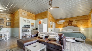 A cozy room with a bed, a sofa, a small table, a microwave, and a refrigerator. - Waynesville Studio w/ Fire Pit & Mountain Views! (Waynesville)