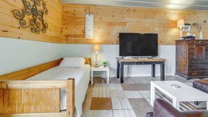 A cozy room with a bed, a TV, a desk, and a cabinet. - Waynesville Studio w/ Fire Pit & Mountain Views! (Waynesville)