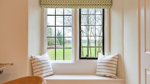 A room with a built-in bench under a window with a view of a green field and trees. - Charlton Down Cottage - Westonbirt - Pet Friendly (Westonbirt)
