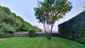 A well-maintained garden with a central lawn, stone walls, and dense foliage on either side. - Charlton Down Cottage - Westonbirt - Pet Friendly (Westonbirt)