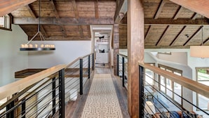 A wooden staircase with a geometric patterned floor leading to a room with a white cabinet and a hanging light fixture.