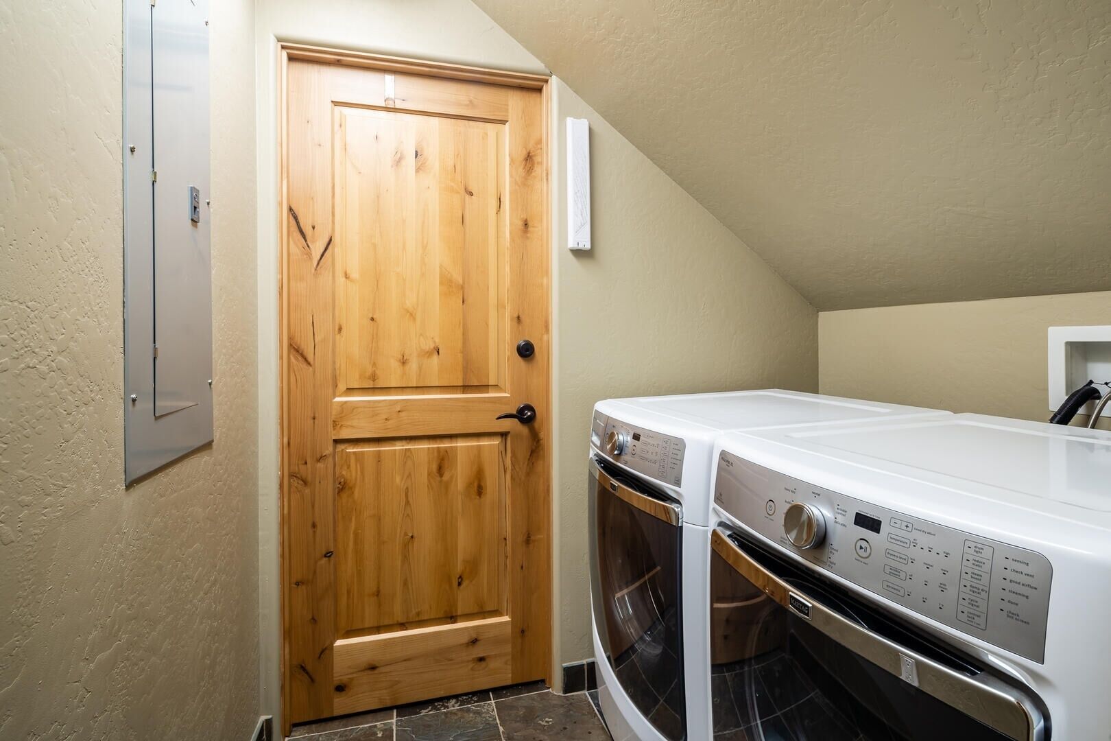 Un cuarto de lavado con puerta de madera, lavadora blanca y secadora.