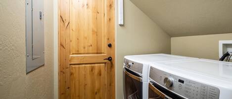Un cuarto de lavado con puerta de madera, lavadora blanca y secadora.