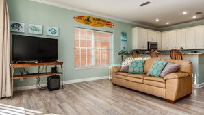 A living room with a TV, sofa, and artwork on the wall. - Mother Of Pearl - Beach Club #205 4 Bedroom Condo by RedAwning (Dauphin Island)