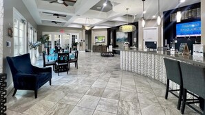 A spacious lobby with a reception desk, seating area, and a large screen displaying room availability.