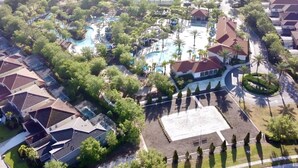 An aerial view of a residential area with a central swimming pool surrounded by greenery and a few buildings.
