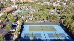 A residential area with a tennis court, houses, and a swimming pool.