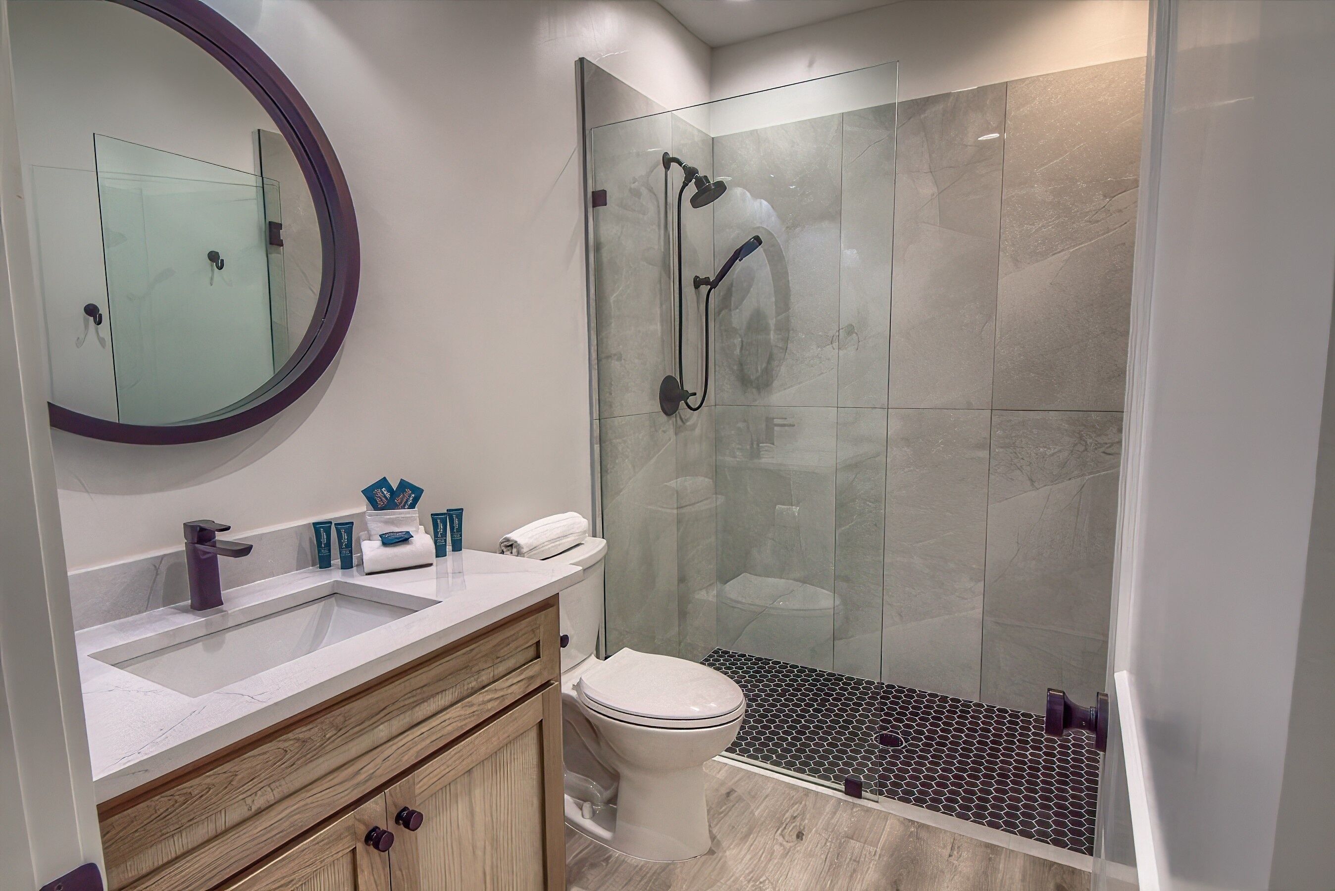 A modern bathroom with a glass-enclosed shower, a white sink, and a wooden vanity.