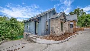 A modern house with a stone foundation, a blue exterior, and a stone chimney.