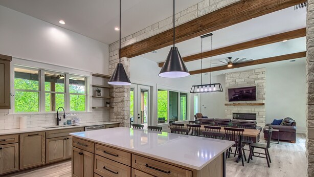 A spacious kitchen with a large island, wooden cabinets, and pendant lighting.