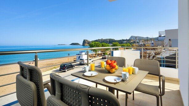 Ein Balkon mit Frühstückstisch mit Blick auf Strand und Meer.