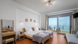Ein Hotelzimmer mit Bett, Schreibtisch, Stuhl, Fernseher und einem Balkon mit Meerblick.